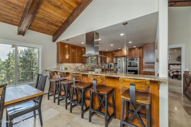 8718 W Sausser Dr, Coeur Dalene, ID 83814 - kitchen featuring island range hood, stainless steel appliances, brown cabinets, light stone countertops, and tasteful backsplash