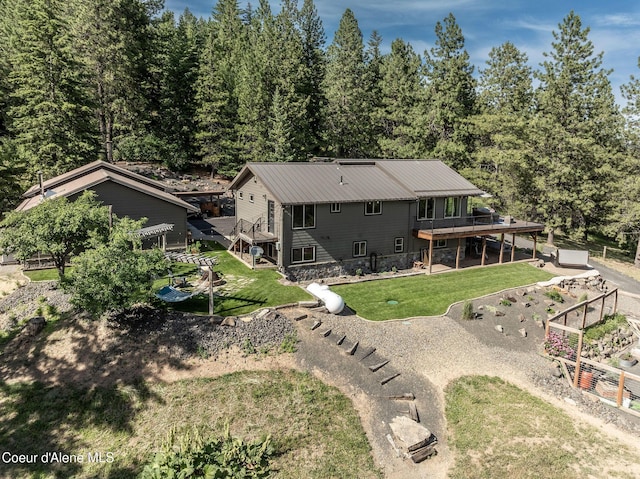 8718 W Sausser Dr, Coeur Dalene, ID 83814 - rear view of property with a wooden deck, a vegetable garden, a yard, and a forest view