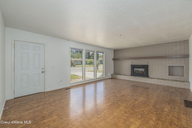 6300 N Sunrise Ter, Coeur Dalene, ID 83815 - unfurnished living room with wood finished floors, a fireplace, and a textured ceiling