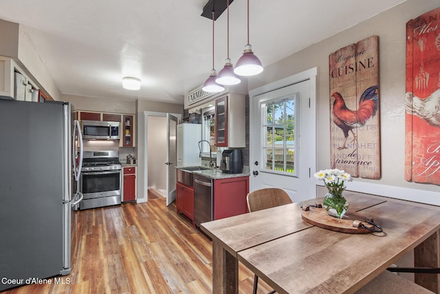 709 E 14th Ave, Post Falls, ID 83854 - kitchen with appliances with stainless steel finishes, light wood-style flooring, glass insert cabinets, hanging light fixtures, and light stone countertops