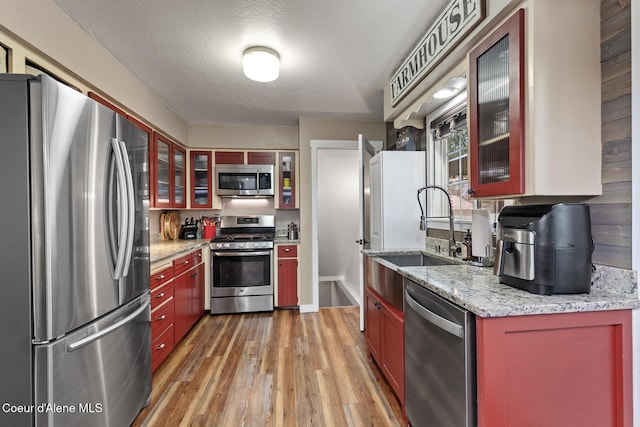 709 E 14th Ave, Post Falls, ID 83854 - kitchen with appliances with stainless steel finishes, light wood-style floors, glass insert cabinets, and light stone counters