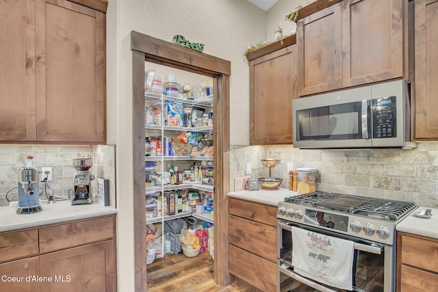 20770 N Penobscot Rd, Rathdrum, ID 83858 - kitchen with stainless steel appliances, tasteful backsplash, light countertops, wood finished floors, and brown cabinetry