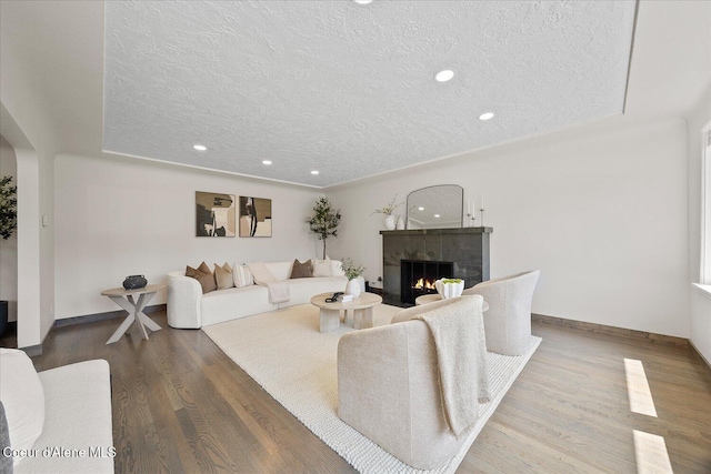 1217 E Montana Ave, Coeur Dalene, ID 83814 - living room featuring a textured ceiling, a tile fireplace, wood finished floors, recessed lighting, and arched walkways