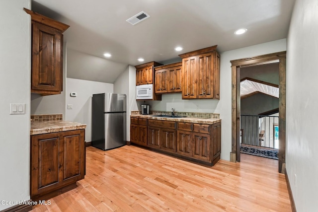 11 Canoe Cv, Dover, ID 83825 - kitchen with freestanding refrigerator, white microwave, vaulted ceiling, light wood-style flooring, and recessed lighting