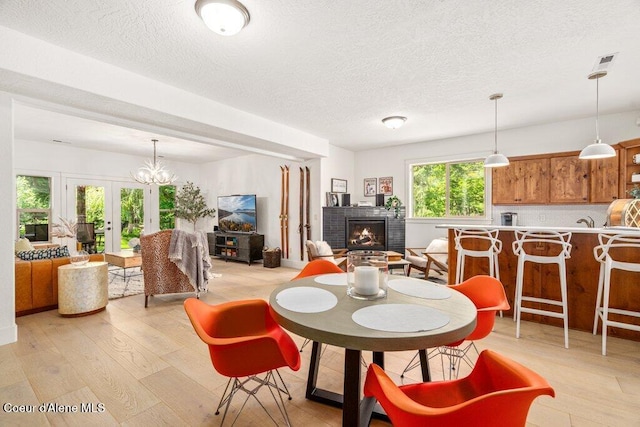 3742 W Cielo View Ct, Coeur Dalene, ID 83814 - dining room featuring light wood-type flooring, a brick fireplace, a textured ceiling, and french doors