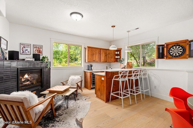 3742 W Cielo View Ct, Coeur Dalene, ID 83814 - kitchen featuring brown cabinets, beverage cooler, healthy amount of natural light, a breakfast bar area, and a textured ceiling