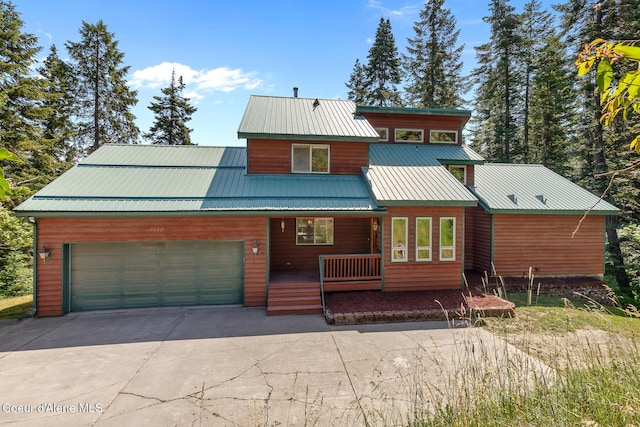 7722 W Clemetson Rd, Coeur Dalene, ID 83814 - rustic home featuring a porch, concrete driveway, a garage, and a metal roof