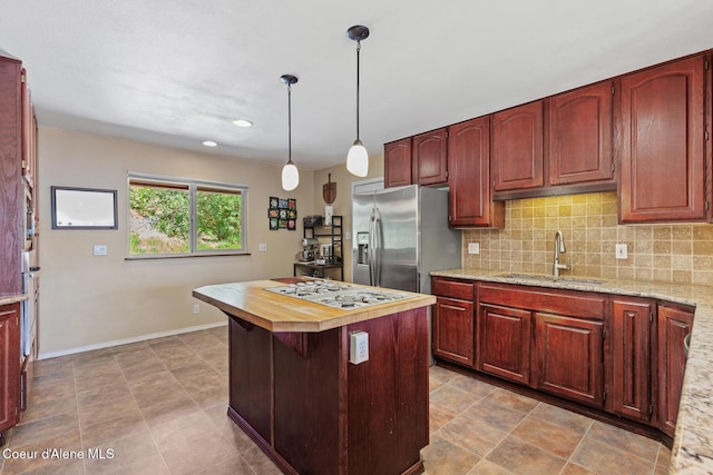 7722 W Clemetson Rd, Coeur Dalene, ID 83814 - kitchen with stainless steel fridge with ice dispenser, white gas stovetop, decorative backsplash, a center island, and hanging light fixtures