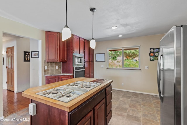 7722 W Clemetson Rd, Coeur Dalene, ID 83814 - kitchen featuring appliances with stainless steel finishes, tasteful backsplash, decorative light fixtures, a center island, and wood counters