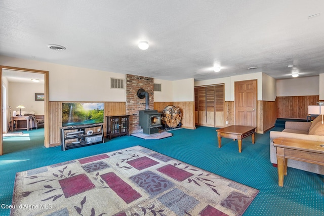 7722 W Clemetson Rd, Coeur Dalene, ID 83814 - living room featuring carpet floors, wood walls, a wainscoted wall, a wood stove, and a textured ceiling