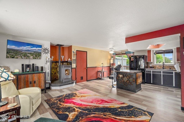 1503 E 3rd Ave, Post Falls, ID 83854 - living room with a wood stove, light wood-style flooring, a ceiling fan, and a textured ceiling