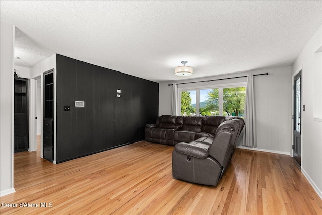 502 W 14th Ave, Post Falls, ID 83854 - living area featuring light wood-type flooring, a textured ceiling, wooden walls, and an accent wall