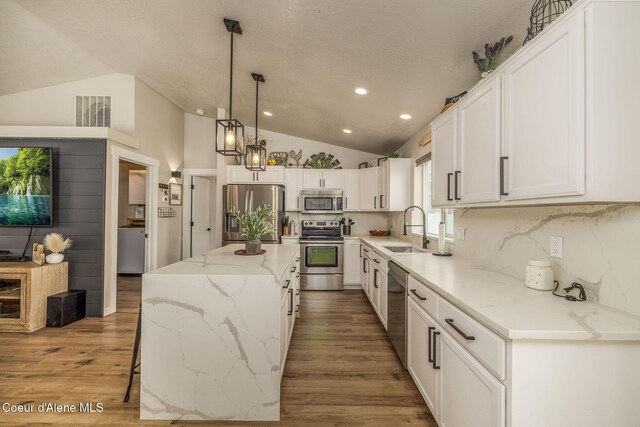13417 N Halley St, Rathdrum, ID 83858 - kitchen featuring stainless steel appliances, lofted ceiling, white cabinetry, light stone counters, and a center island
