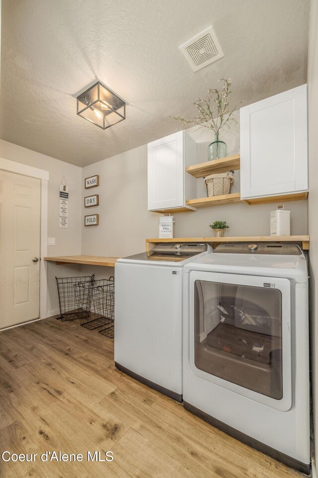 13417 N Halley St, Rathdrum, ID 83858 - laundry room with cabinet space, light wood-type flooring, washer and dryer, and a textured ceiling