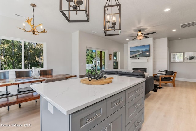 52 Peggys Ct, Dover, ID 83825 - kitchen with gray cabinets, a chandelier, open floor plan, a fireplace, and light wood finished floors