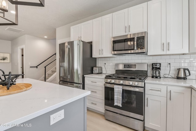 52 Peggys Ct, Dover, ID 83825 - kitchen with appliances with stainless steel finishes, recessed lighting, tasteful backsplash, white cabinets, and light stone counters