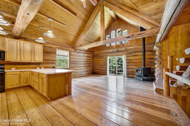 4900 E Hudlow Rd, Hayden, ID 83835 - kitchen with open floor plan, light brown cabinetry, black appliances, a peninsula, and a wood stove