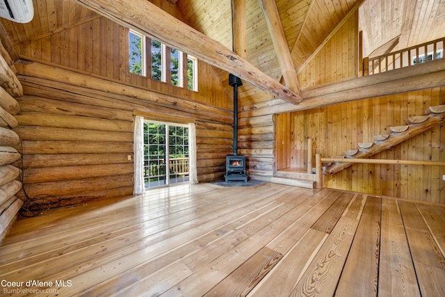 4900 E Hudlow Rd, Hayden, ID 83835 - unfurnished living room with a wood stove, an AC wall unit, high vaulted ceiling, hardwood / wood-style flooring, and log walls
