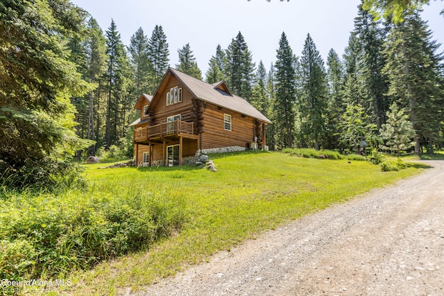 4900 E Hudlow Rd, Hayden, ID 83835 - view of side of home featuring log exterior, a deck, a wooded view, dirt driveway, and a yard