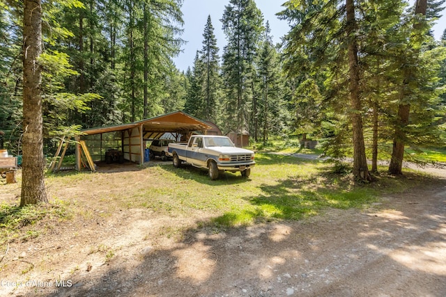 4900 E Hudlow Rd, Hayden, ID 83835 - view of yard featuring dirt driveway, a detached carport, and a forest view