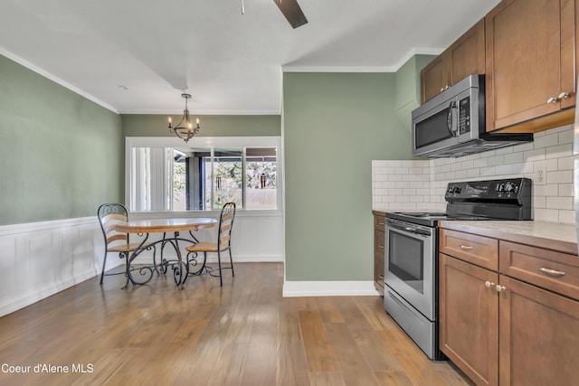 32271 N 5th Ave, Spirit Lake, ID 83869 - kitchen featuring stainless steel appliances, brown cabinets, crown molding, a chandelier, and tasteful backsplash