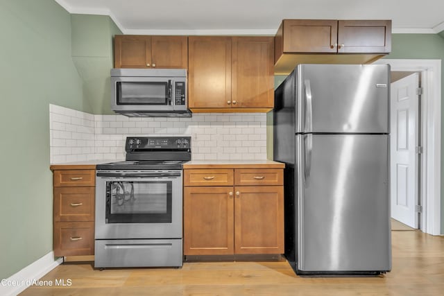 32271 N 5th Ave, Spirit Lake, ID 83869 - kitchen featuring stainless steel appliances, light countertops, ornamental molding, backsplash, and brown cabinets