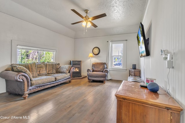 32271 N 5th Ave, Spirit Lake, ID 83869 - living room featuring hardwood / wood-style flooring, a ceiling fan, a wood stove, vaulted ceiling, and a textured ceiling