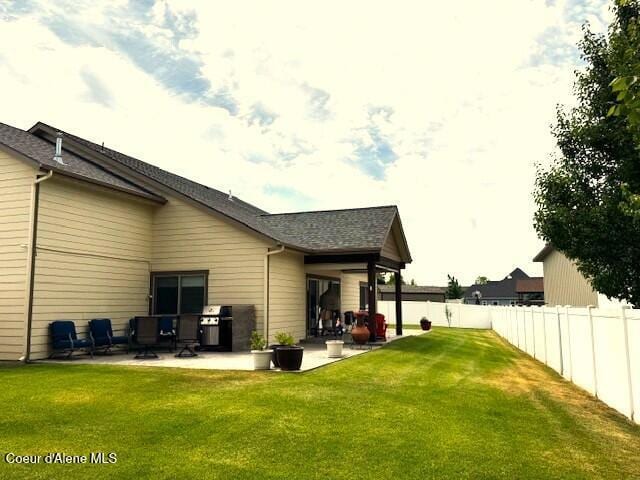 1402 W Wayward Cir, Post Falls, ID 83854 - back of property featuring a patio area, a fenced backyard, and roof with shingles