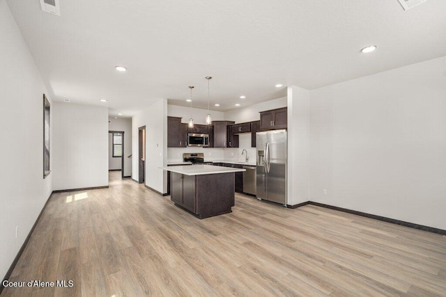 8 Potlatch Loop, Priest River, ID 83856 - kitchen featuring appliances with stainless steel finishes, dark brown cabinets, light countertops, light wood-style flooring, and a kitchen island