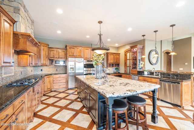 5841 W Clemetson Rd, Coeur Dalene, ID 83814 - kitchen featuring appliances with stainless steel finishes, inlaid floor details, recessed lighting, a center island with sink, and dark stone countertops