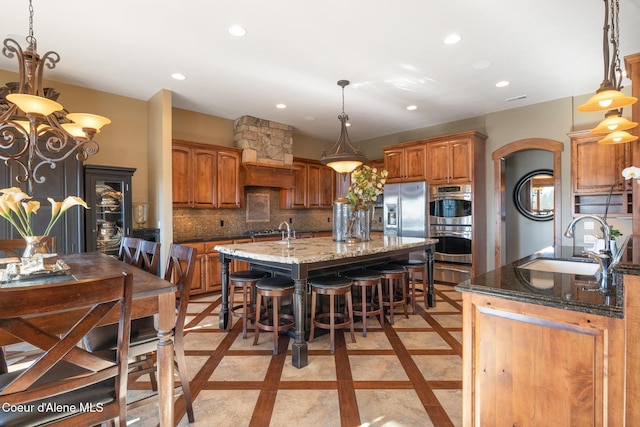 5841 W Clemetson Rd, Coeur Dalene, ID 83814 - kitchen featuring an island with sink, inlaid floor details, recessed lighting, appliances with stainless steel finishes, and light stone counters