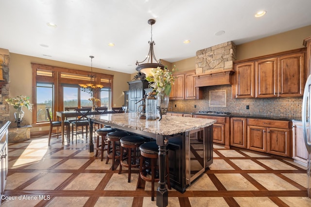 5841 W Clemetson Rd, Coeur Dalene, ID 83814 - kitchen with inlaid floor details, a center island, light stone countertops, brown cabinetry, and recessed lighting