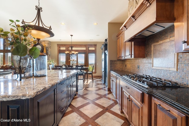 5841 W Clemetson Rd, Coeur Dalene, ID 83814 - kitchen with gas cooktop, premium range hood, decorative light fixtures, inlaid floor details, and tasteful backsplash