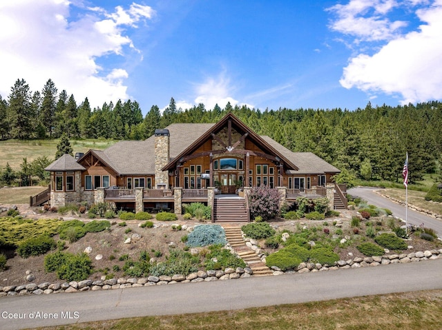 5841 W Clemetson Rd, Coeur Dalene, ID 83814 - view of front facade featuring stairway, stone siding, a porch, a forest view, and a chimney