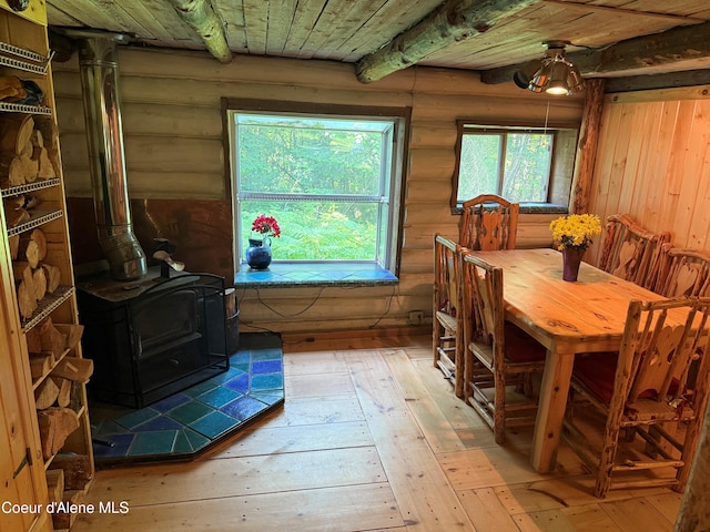 1283 N Wrenco Rd, Sandpoint, ID 83864 - dining room with rustic walls, a wood stove, light wood-style floors, and wood ceiling