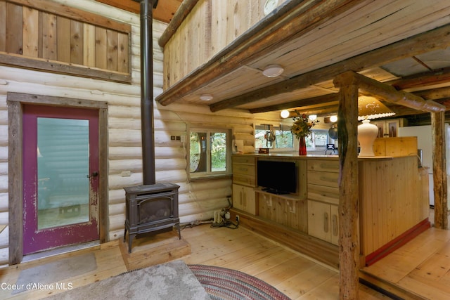 1283 N Wrenco Rd, Sandpoint, ID 83864 - living area featuring a wood stove, rustic walls, light wood-style flooring, and beamed ceiling