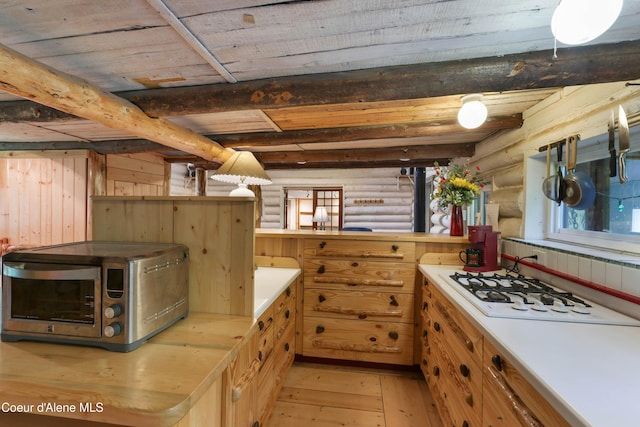 1283 N Wrenco Rd, Sandpoint, ID 83864 - kitchen with rustic walls, light wood finished floors, light countertops, white gas stovetop, and a wood ceiling with exposed beams