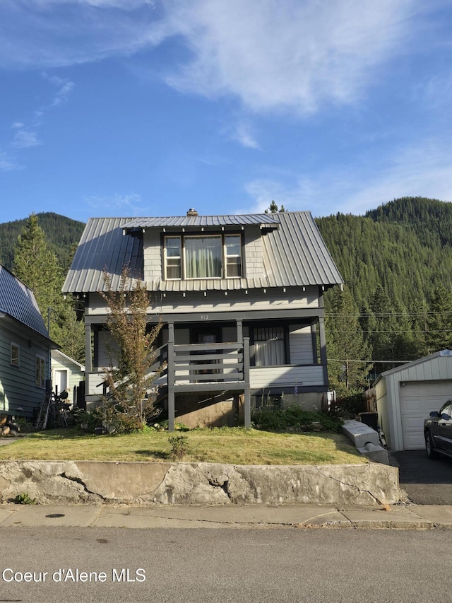 312 Park St, Mullan, ID 83846 - view of front facade with a metal roof, an outbuilding, a wooded view, a mountain view, and asphalt driveway