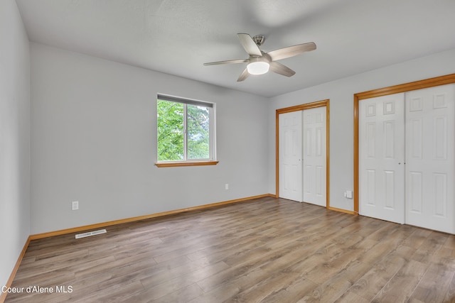 2665 W Broadmoore Dr, Hayden, ID 83835 - unfurnished bedroom featuring two closets, light wood-style flooring, and a ceiling fan