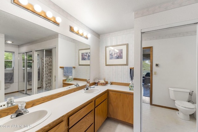 7605 W Sanders Rd, Coeur Dalene, ID 83814 - bathroom with double vanity, a textured ceiling, and wallpapered walls