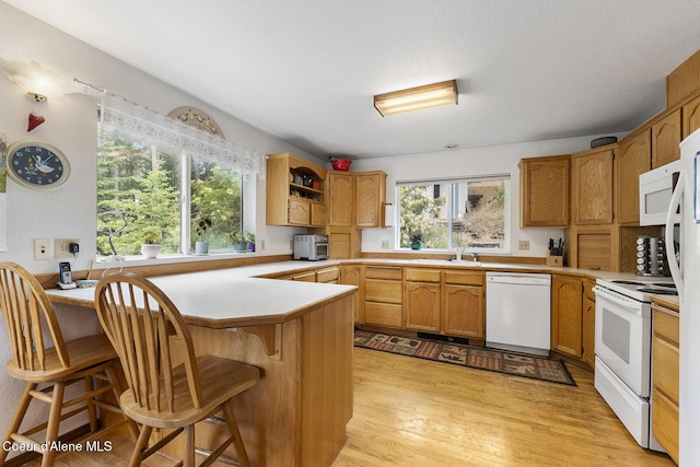 7605 W Sanders Rd, Coeur Dalene, ID 83814 - kitchen featuring white appliances, a peninsula, light wood-type flooring, and light countertops