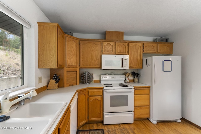 7605 W Sanders Rd, Coeur Dalene, ID 83814 - kitchen featuring white appliances, light countertops, light wood-type flooring, and brown cabinetry
