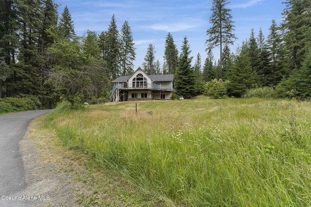 7605 W Sanders Rd, Coeur Dalene, ID 83814 - view of front of home with a deck, stairway, asphalt driveway, and a view of trees