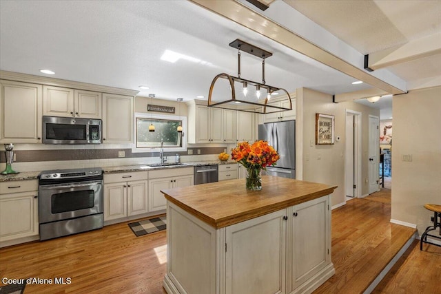 12321 N Sherwood Ct, Hayden, ID 83835 - kitchen featuring stainless steel appliances, butcher block countertops, cream cabinetry, a kitchen island, and recessed lighting