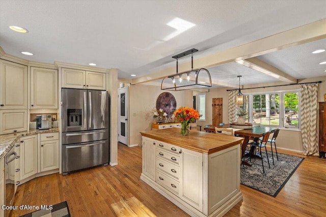 12321 N Sherwood Ct, Hayden, ID 83835 - kitchen with stainless steel appliances, cream cabinets, butcher block countertops, light wood finished floors, and a center island