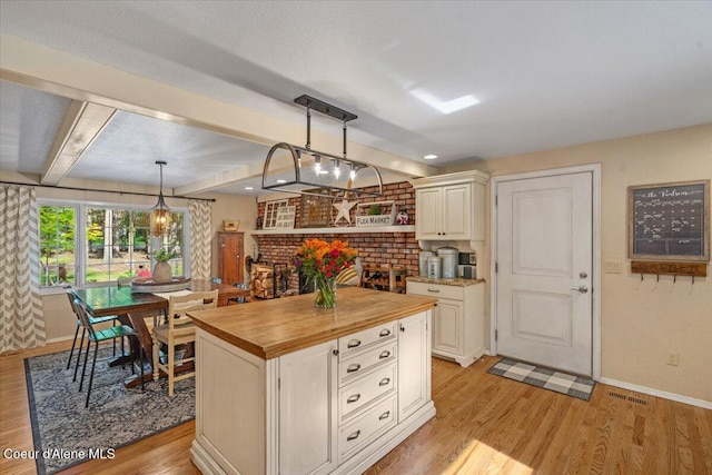 12321 N Sherwood Ct, Hayden, ID 83835 - kitchen featuring wooden counters, light wood finished floors, hanging light fixtures, and a center island
