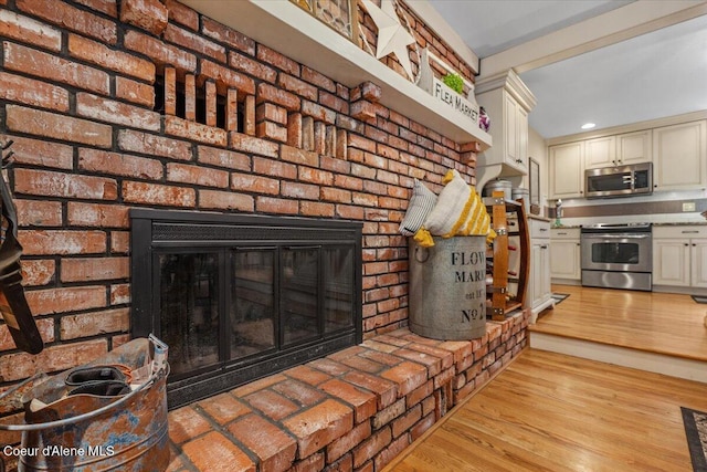 12321 N Sherwood Ct, Hayden, ID 83835 - detailed view of stainless steel appliances, a brick fireplace, wood finished floors, and recessed lighting