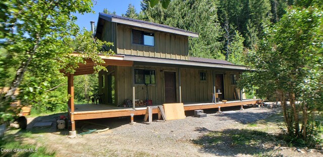 1007 Ruby Creek Rd, Naples, ID 83847 - view of front of house featuring board and batten siding, covered porch, a forest view, and a wooden deck