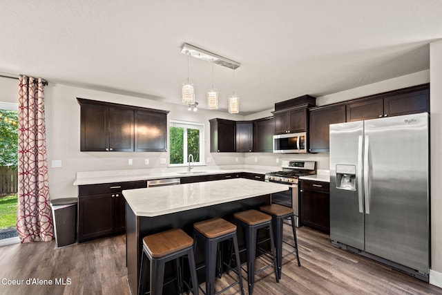 120 E Walnut Ave, Coeur Dalene, ID 83814 - kitchen with stainless steel appliances, wood finished floors, dark brown cabinetry, light countertops, and a center island