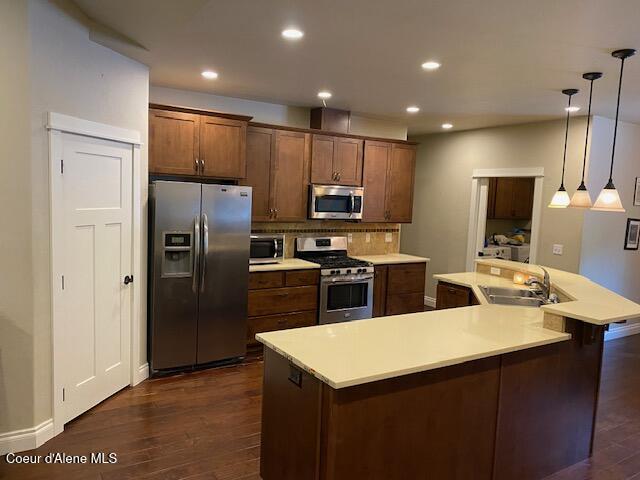 4310 Burns Ct, Sandpoint, ID 83864 - kitchen featuring appliances with stainless steel finishes, dark wood-style floors, light countertops, recessed lighting, and a large island with sink
